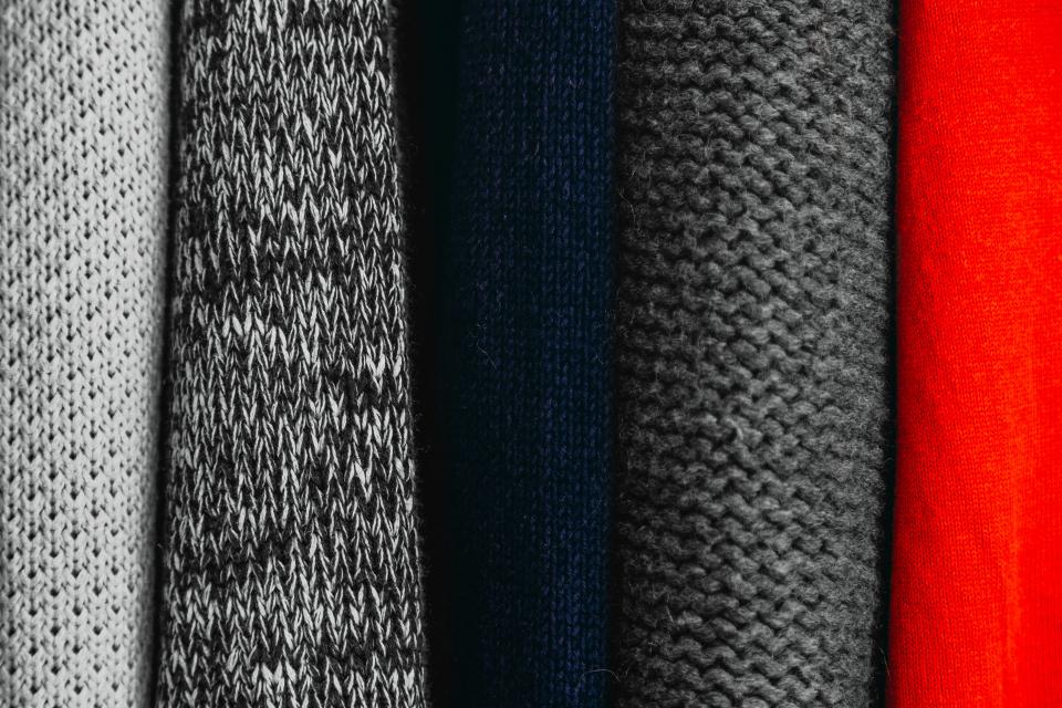 Stack of folded knit sweaters in grey, navy and red