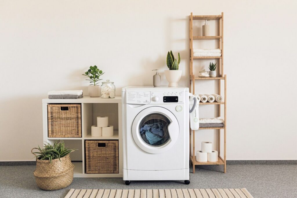 Front-load washer beside shelves with folded towels