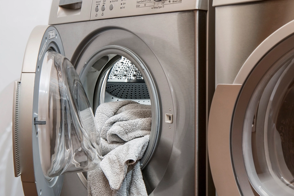 Washing machine with open door and a gray towel inside